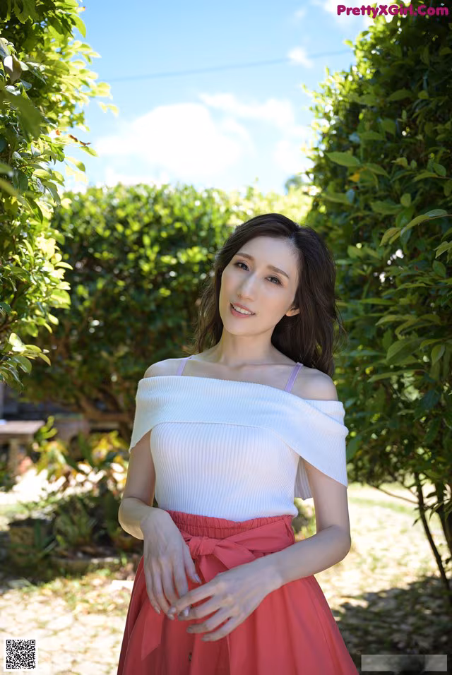 A woman in a white top and red skirt posing for a picture.