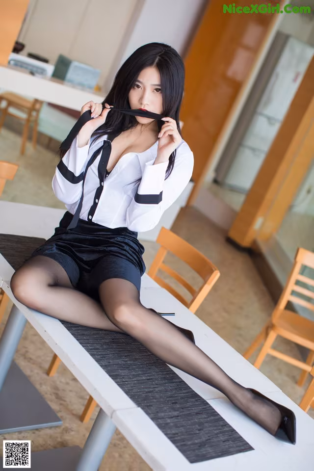 A woman sitting at a table with a tie around her neck.