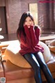 A woman sitting on top of a brown couch.