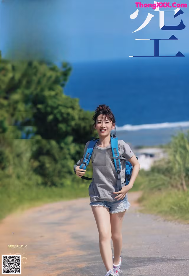 A woman walking down a road with a backpack.