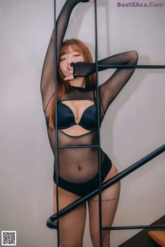 A woman in a black lingerie posing on a staircase.