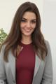 A woman in a gray blazer posing for a picture.