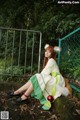 A woman in a green and white dress sitting on a rock.