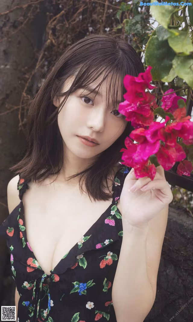 A woman in a black dress holding a pink flower.