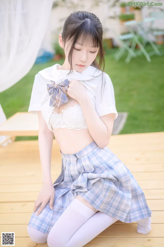 A young woman in a school uniform sitting on a wooden deck.
