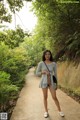 A woman standing on a sidewalk in a park.