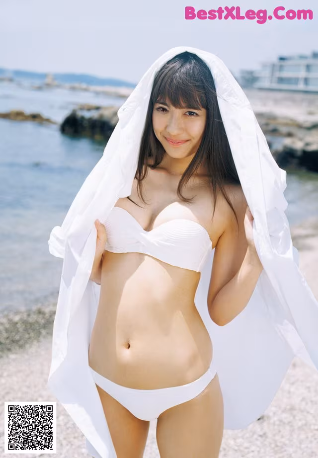 A woman in a white bikini standing on a beach.