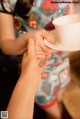 A woman holding a cup and saucer in her hand.