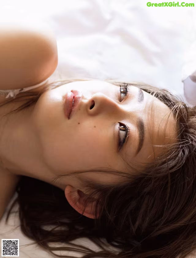 A woman laying on a bed with her eyes closed.