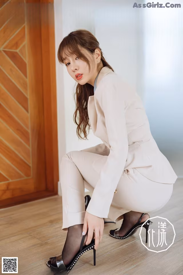 A woman in a white suit crouching on the floor.