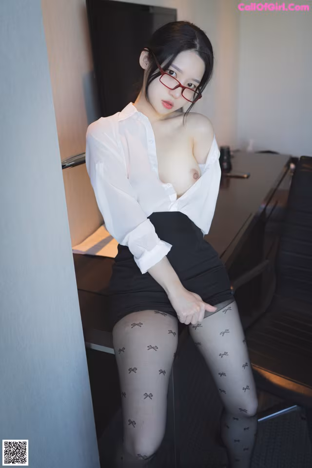 A woman in a white shirt and black skirt posing for the camera.