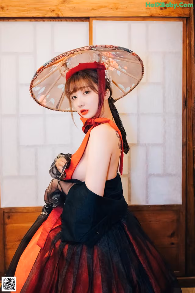 A woman in a black and red dress holding an umbrella.