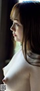 A woman with long brown hair is looking out a window.