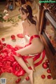 A woman in a red lingerie sitting on the floor next to a fireplace.