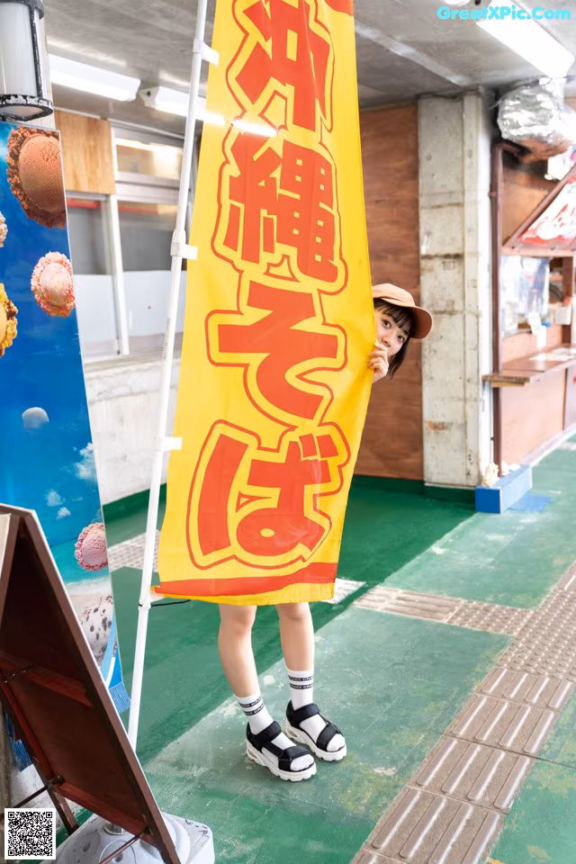 A woman standing in front of a yellow and red banner.