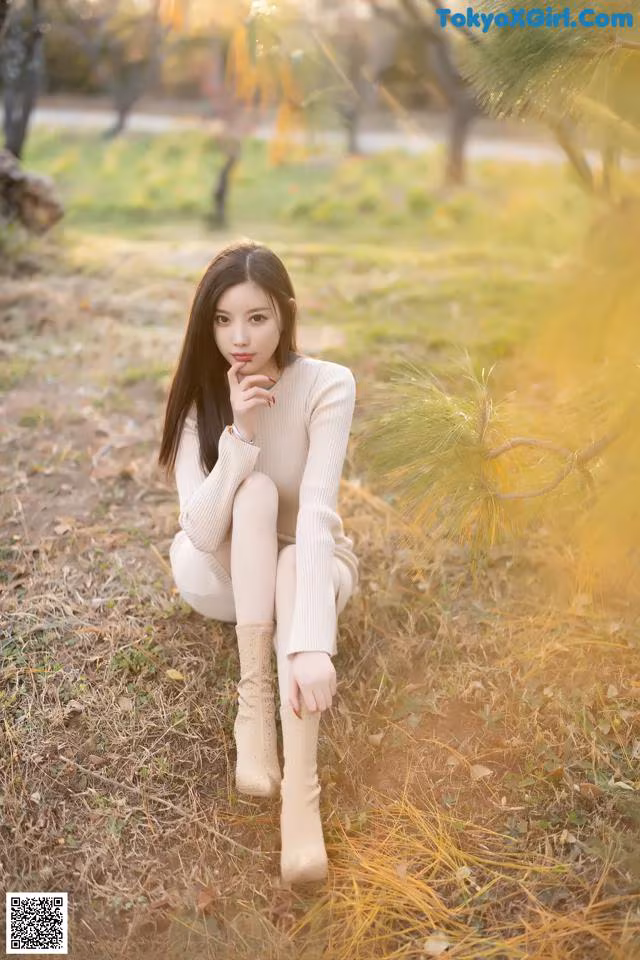 A woman sitting on the ground in a park.