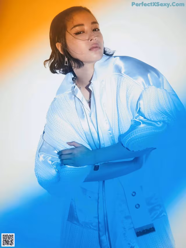A woman in a white jacket is posing for a magazine.