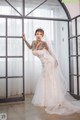 A woman in a wedding dress standing in front of a window.